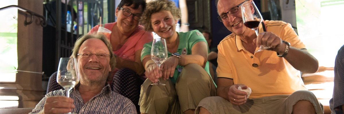 Personen sitzen auf der Rathaustreppe mit Weingläsern in den Händen
