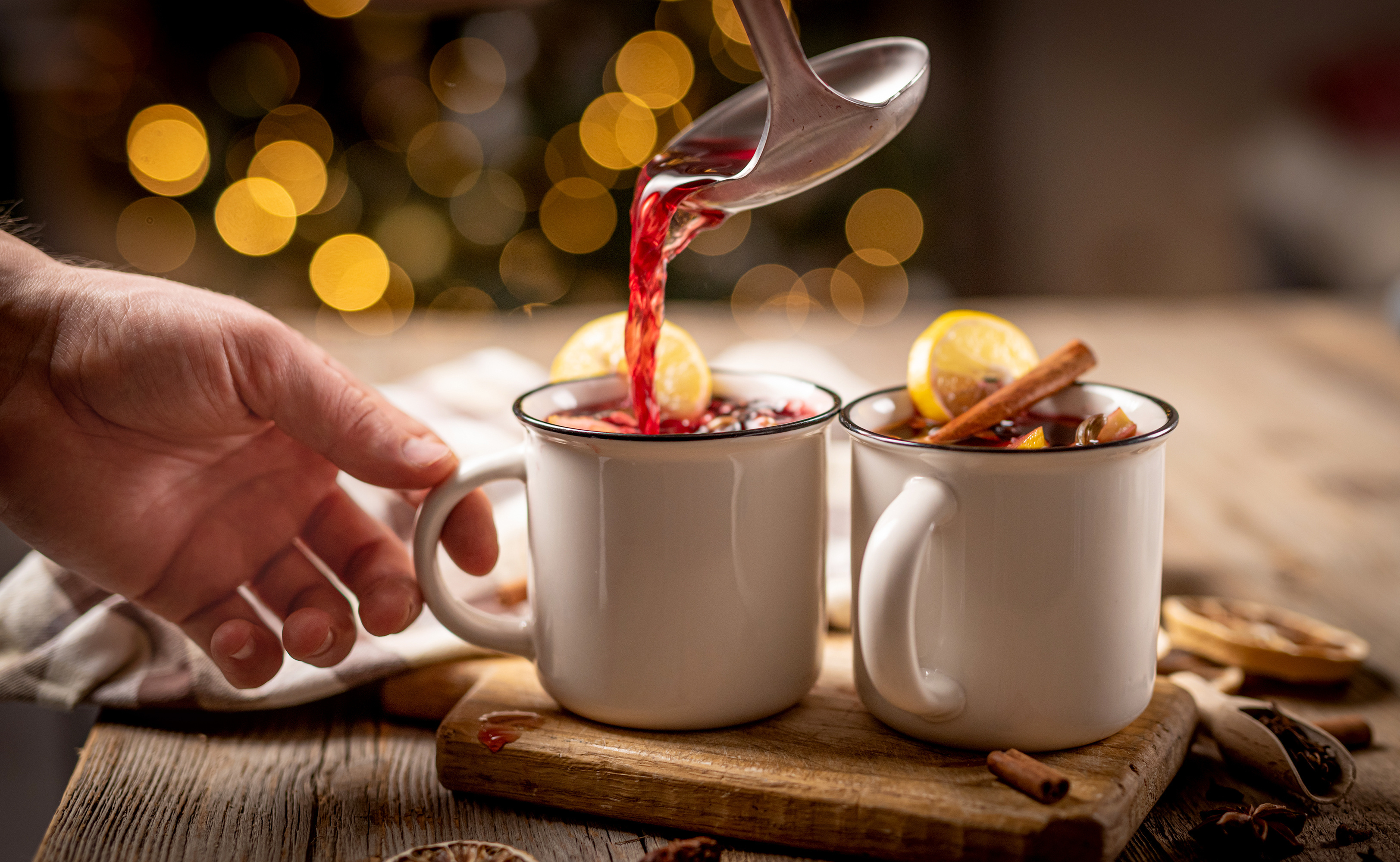Pouring hot mulled wine into steel cups Glühwein wird in Tassen eingegossen
