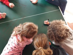 Kinder beugen sich über eine Tischtennisplatte