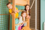 Portrait of smiling kids on a wooden ladder Drei kinder auf einem Klettergerüßt