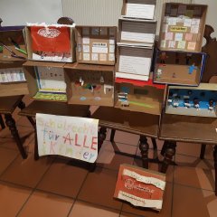 Ein Tisch mit vielen gebastelten Sachen und einem Papier, mit der Aufschrift: "Schulrecht für alle Kinder"