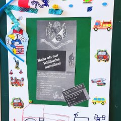 Ein gebasteltes Bild, mit aufgeklebten und aufgemalten Sachen, und einem Flyer, der Feuerwehr Geisenheim