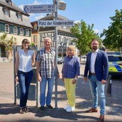 Der Bürgermeister und andere Menschen vor den Straßenschild Platz der Kinderrechte