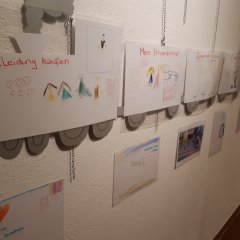 Ein Zug aus Papier, an die Wand geklebt, mit mehr gemalten Bildern