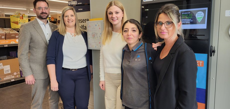Bürgermeister Christian Aßmann, Nicole Rakusa (Leiterin Kindertagesstätte Marienthaler Knirpsenland), Alexandra Albes (Regionalverkaufsleiterin ALDI Süd), Marta Sakur (stellvertretende Filialleiterin) sowie Christina Roleder (Leiterin Amt für Bürger und Soziales) in der ALDI Filiale Rüdesheim