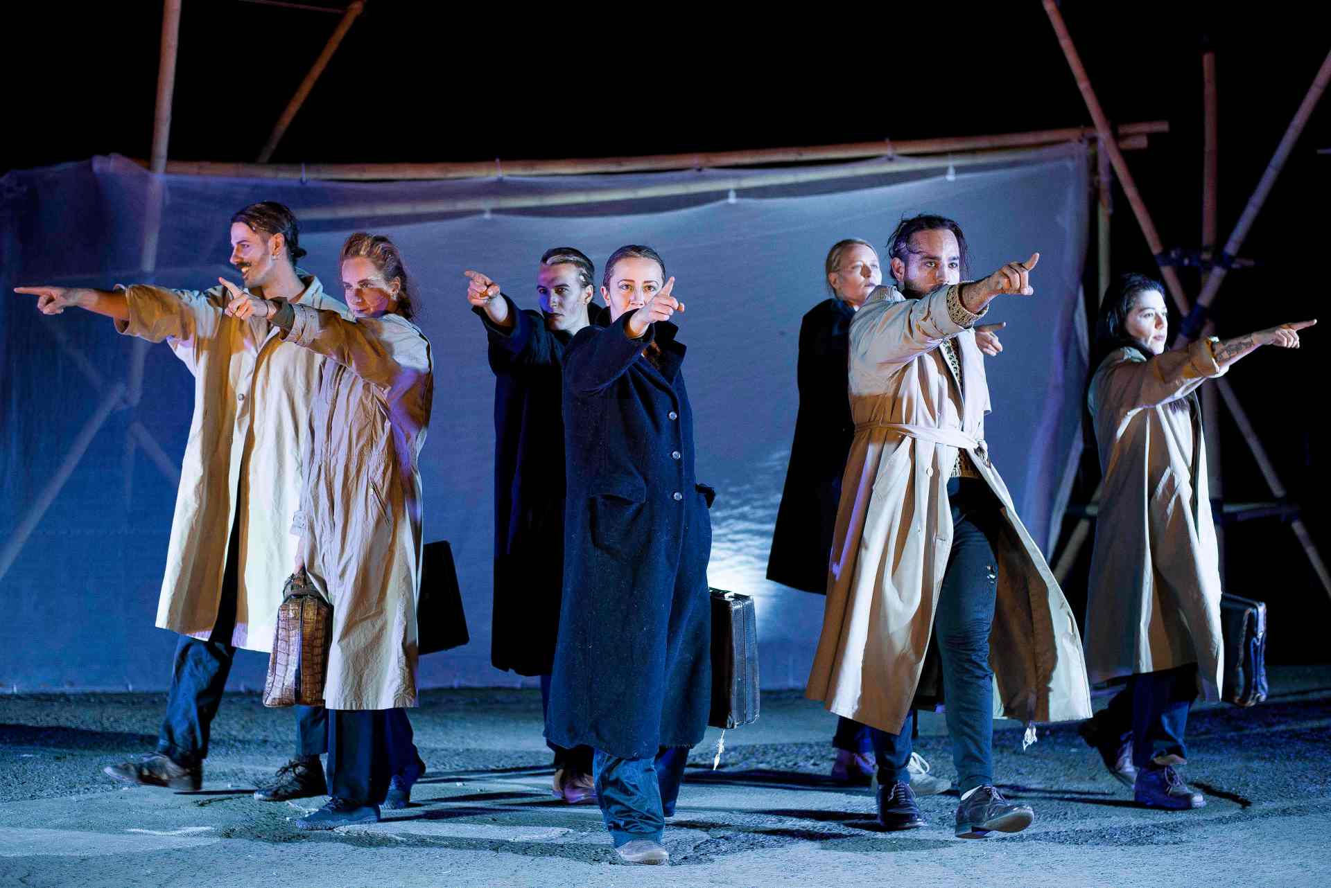 Szene des Stücks TREES. Personen in Mänteln deuten mit ausgestreckter Hand nach vorne