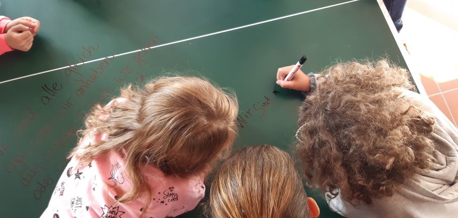 Kinder beugen sich über eine Tischtennisplatte