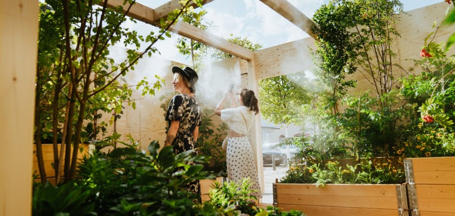 Die Klima-Kiste Geisenheim von innen. Viele Pflanzen. Zwei Frauen sehen sich um.