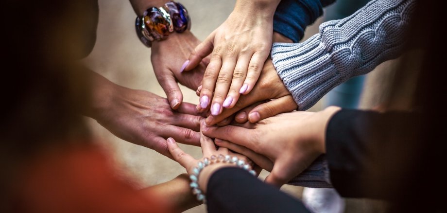 Viele Hände liegen übereinander.