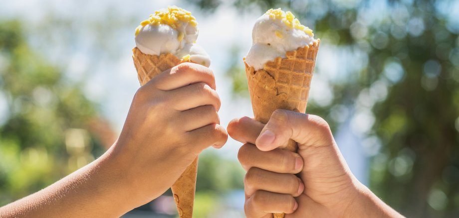 Zwei Hände die mit Eiswaffeln anstoßen