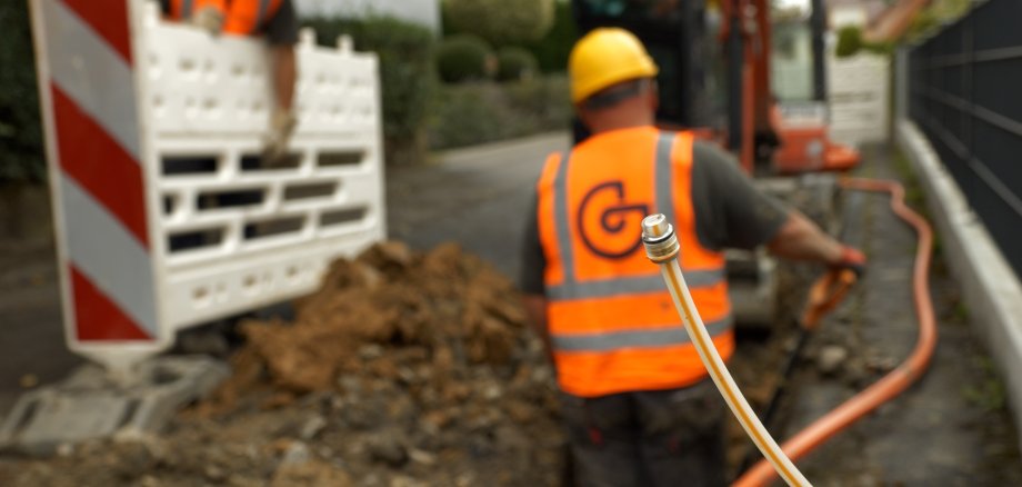 Arbeiter der Giga Netz verlegt Glasfaserkabel im Graben
