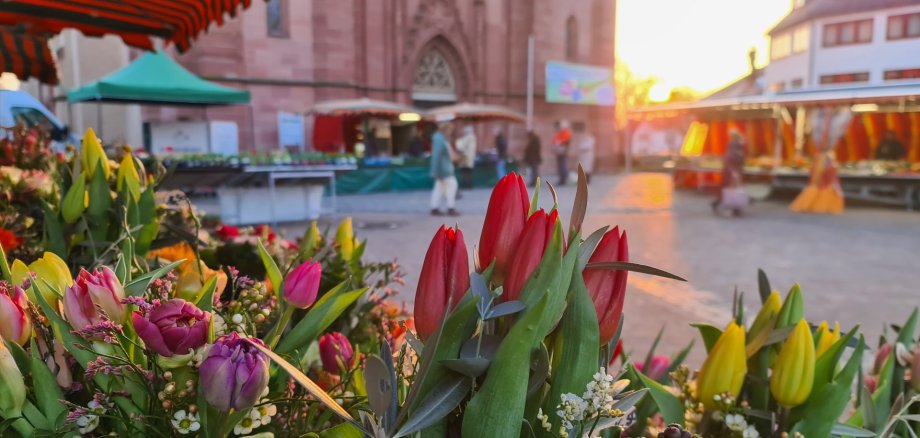 Wochenmarkt bei Sonnenaufgang mit Blumen im Vordergrund