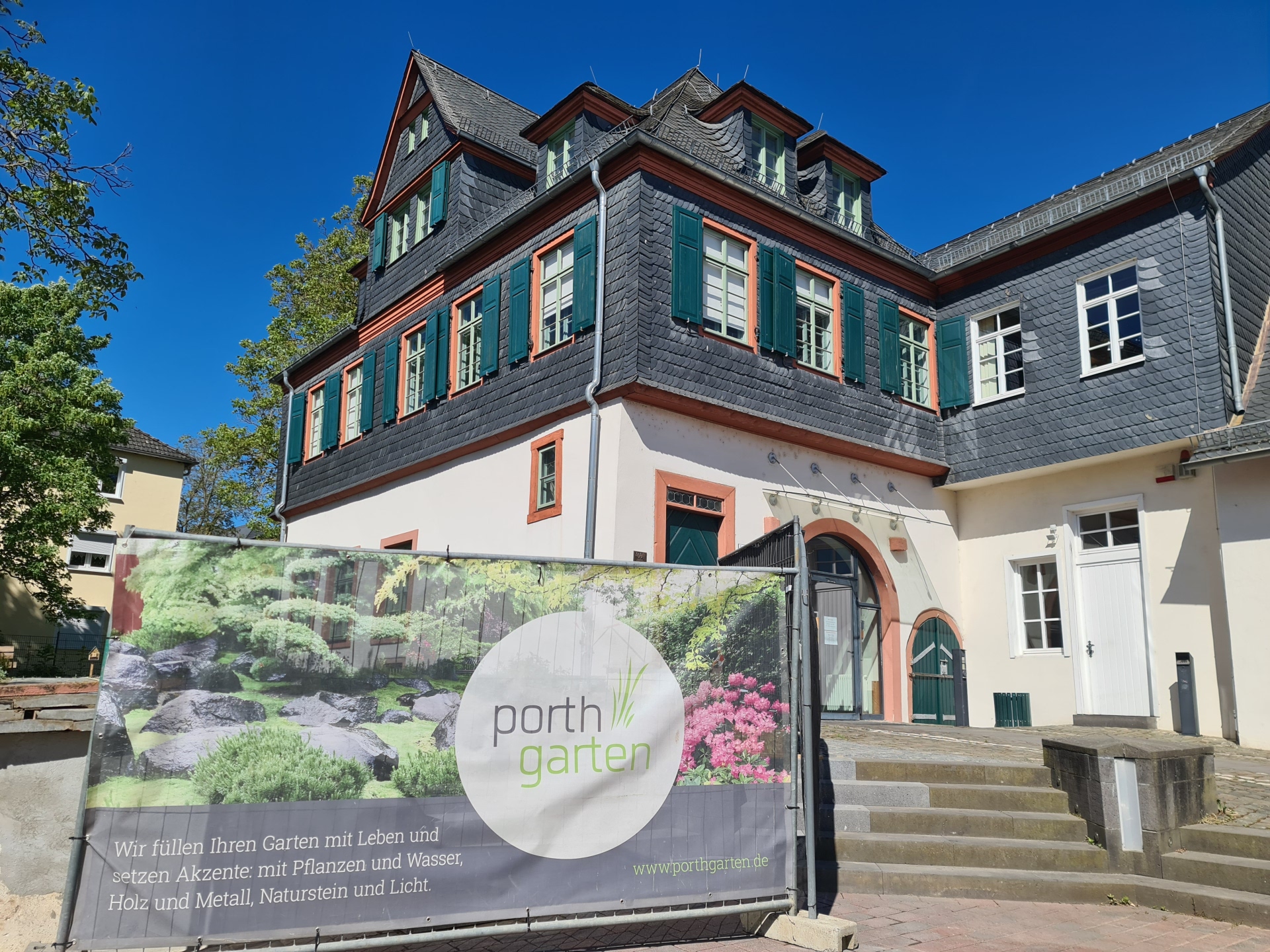 Bachelin-Garten mit Bachelin-Haus im Hintergrund und Bauzaunbanner