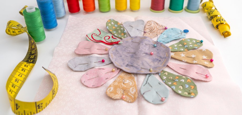 Ready to stitched flower applique quilt, yellow measuring tape and spools of multicolor threads; concept about reuse material for handmade craft Fledermaus