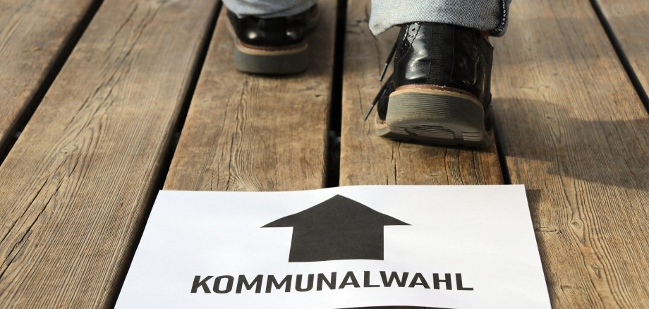 ein Schild, was den Weg zu der Kommunalwahl zeigt und eine Person, die in diese Richtung geht