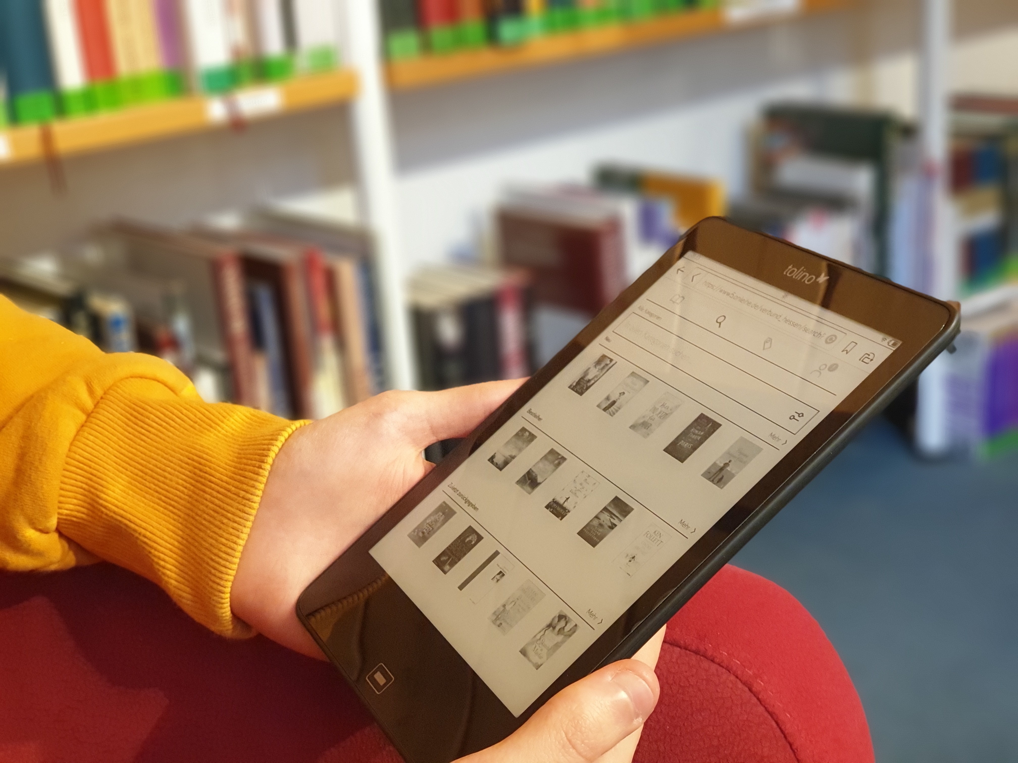 Ein iPad in der Hand, auf dem Bücher angezeigt werden.