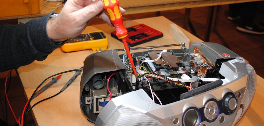 Hand die mit Schraubenzieher Kassettenrekorder repariert